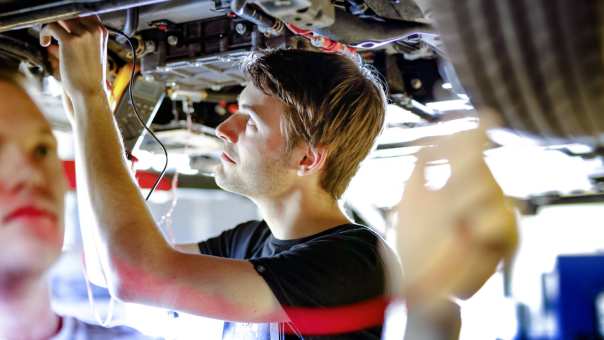 studenten werken aan auto op hefbrug