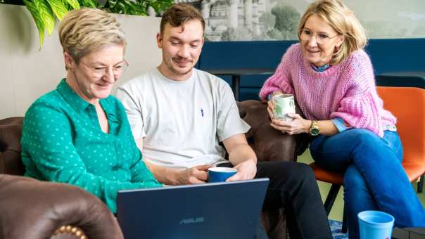 Drie studenten kijken samen aandachtig op de laptop.