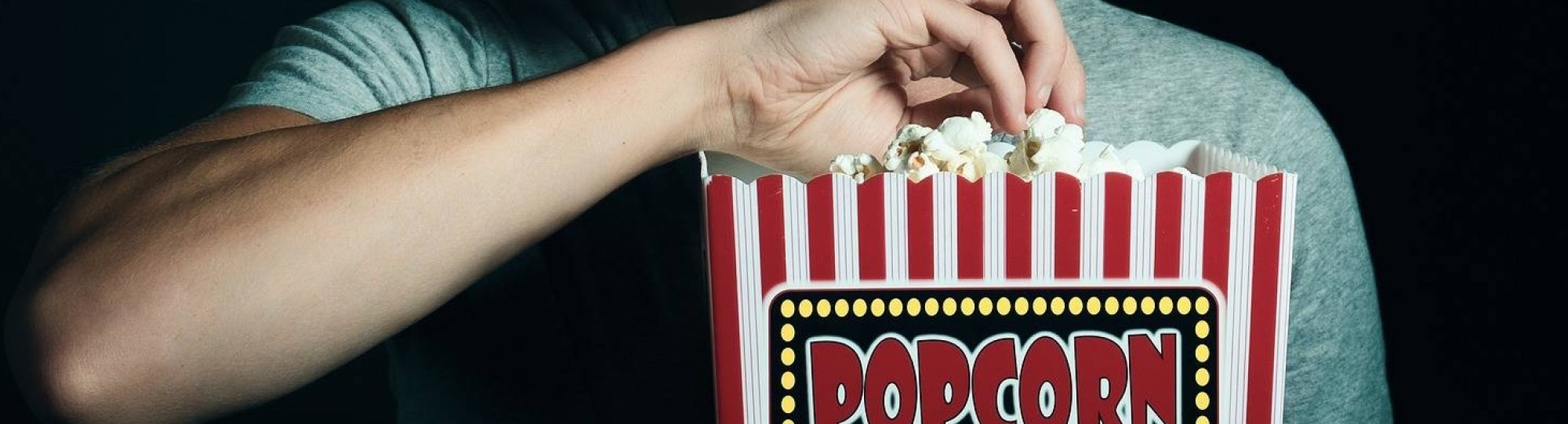 Man eet popcorn terwijl hij film kijkt