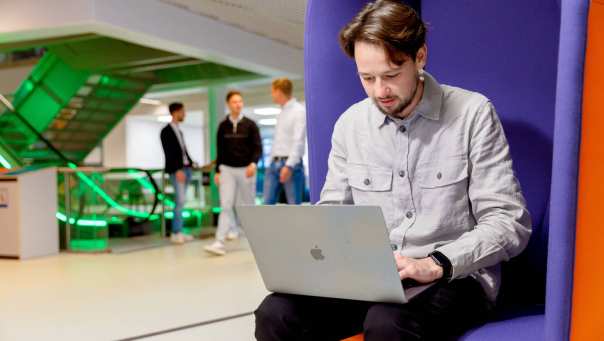 Deeltijd student Commerciële Economie aan het werk op laptop in de gang. 