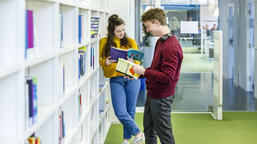 Twee studenten Pedagogiek lezen boek bibliotheek