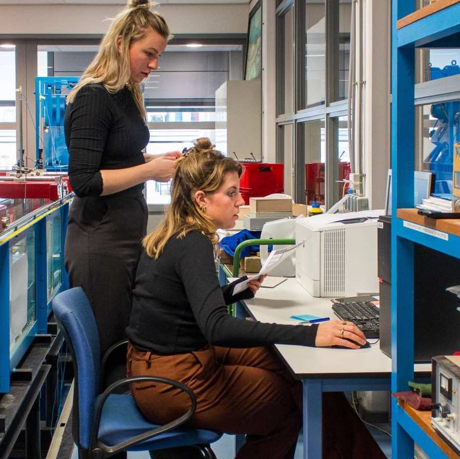 Nienke Maas en Brechtje Kraaijvanger doen een proef in het waterlab met het model van een woonboot