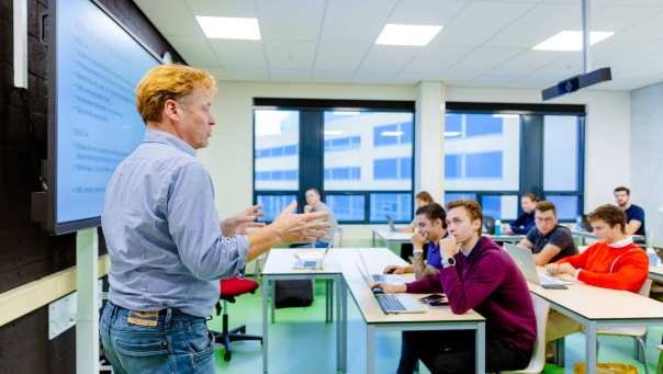 Docent geeft les aan klas duaal studenten Commerciële Economie.