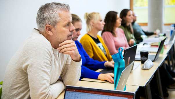 Foto van Master Ontwerpen van Eigentijds Leren. Close-up van één masterstudent die gefocust kijkt met andere masterstudenten vaag op de achtergrond. 