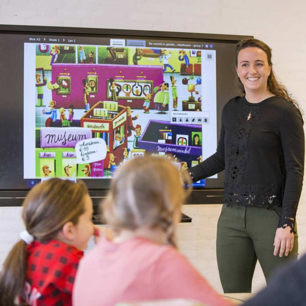 Pabo-docente geeft les aan haar klas en gebruikt daarbij een groot beeldscherm.