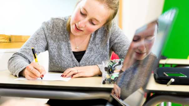 Lachende ALPO student aan het schrijven