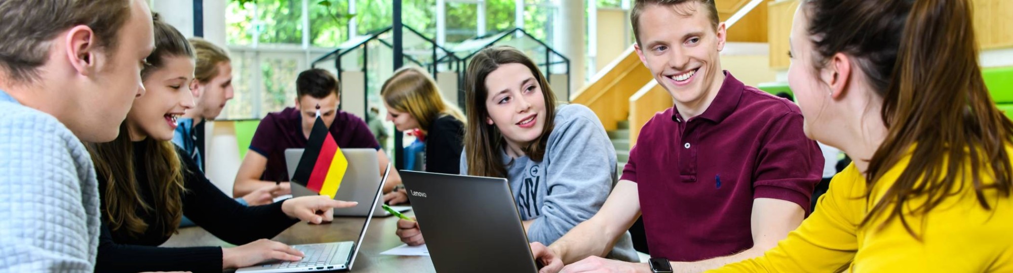 Studenten leraar Duits zitten aan een grote tafel in de kantine van het I/O gebouw en zijn aan het overleggen. 