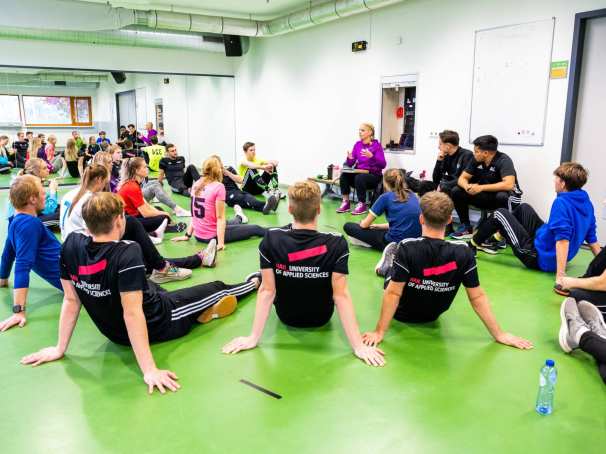 Studenten luisteren in de sportles naar docente.