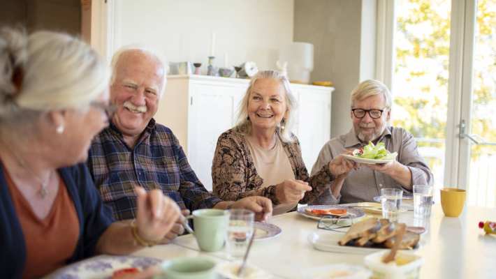 Groep ouderen aan tafel tijdens het ontbijt in een verpleeghuis