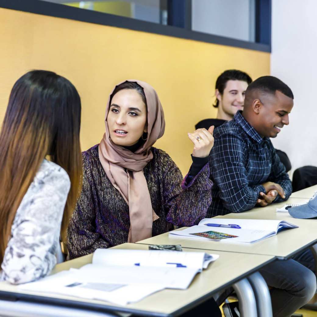 4 studenten Social Work zijn aanwezig in een college en in gesprek met elkaar.