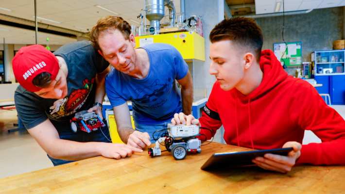 Studenten en docent spelen met auto