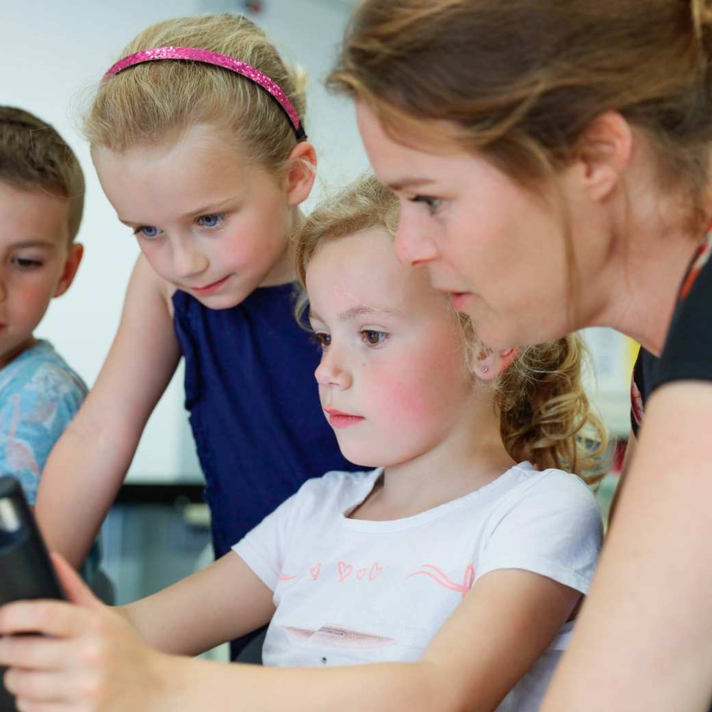 Kinderen met juf achter Ipad