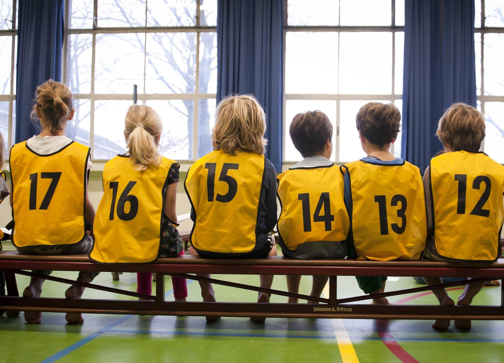 in een gymzaal met hesjes aan op de rug gefotografeerd