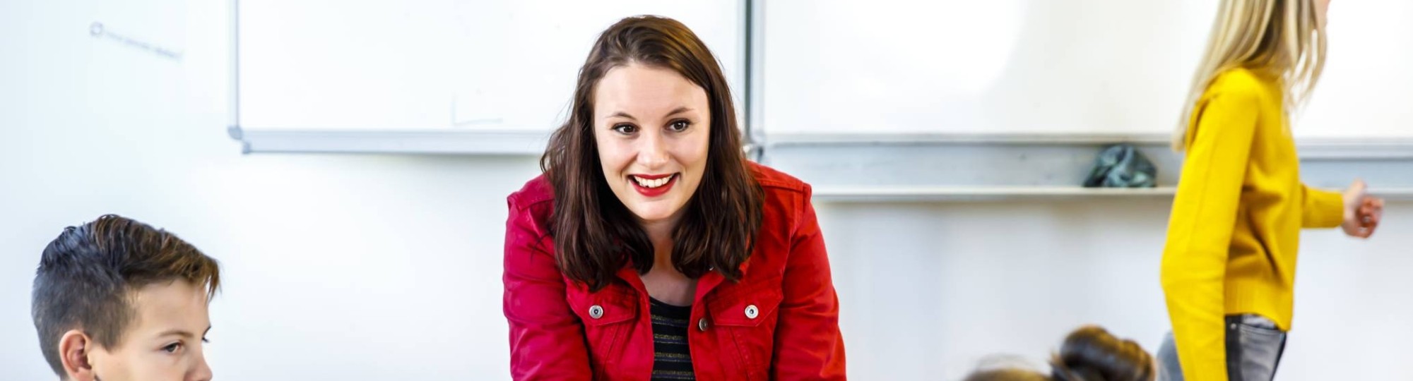 Docent luistert naar haar drie studenten die aan de tafel zitten te overleggen.