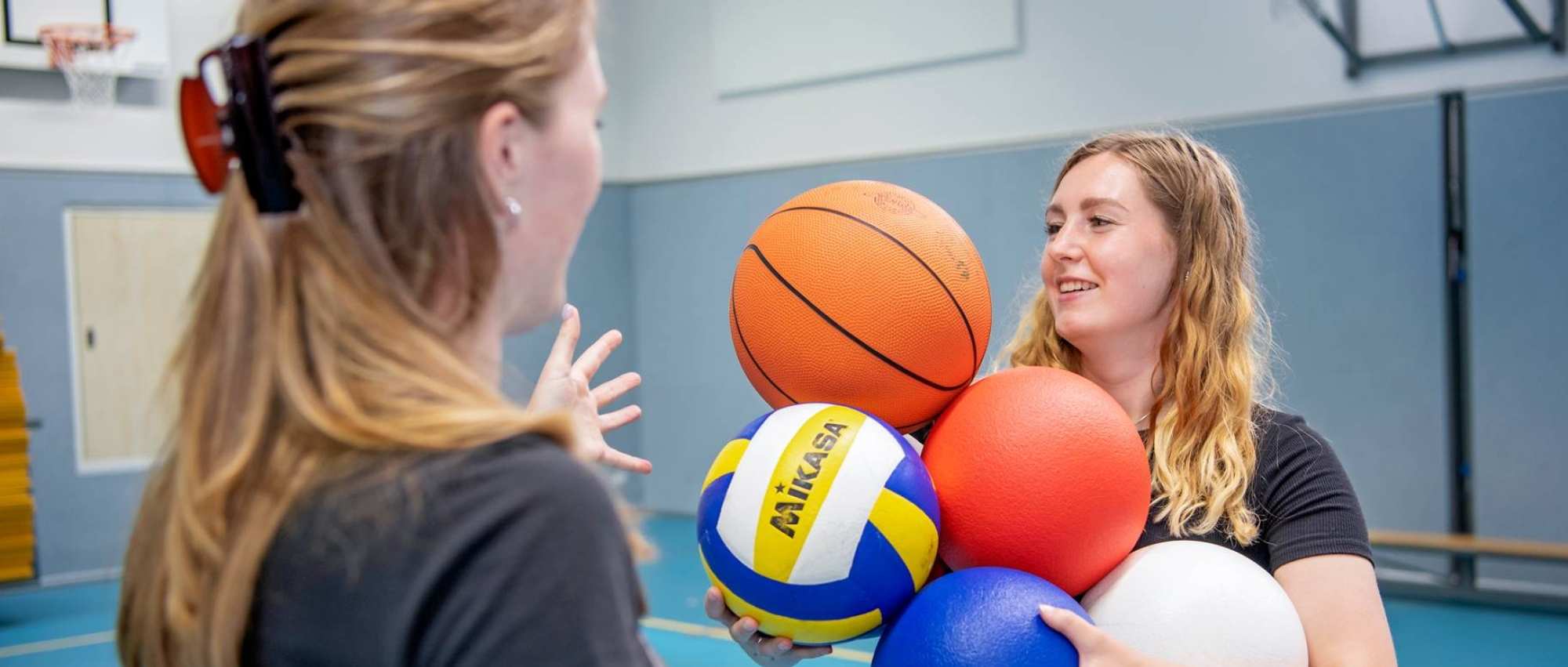 2 meisjes met ballen in gymlokaal