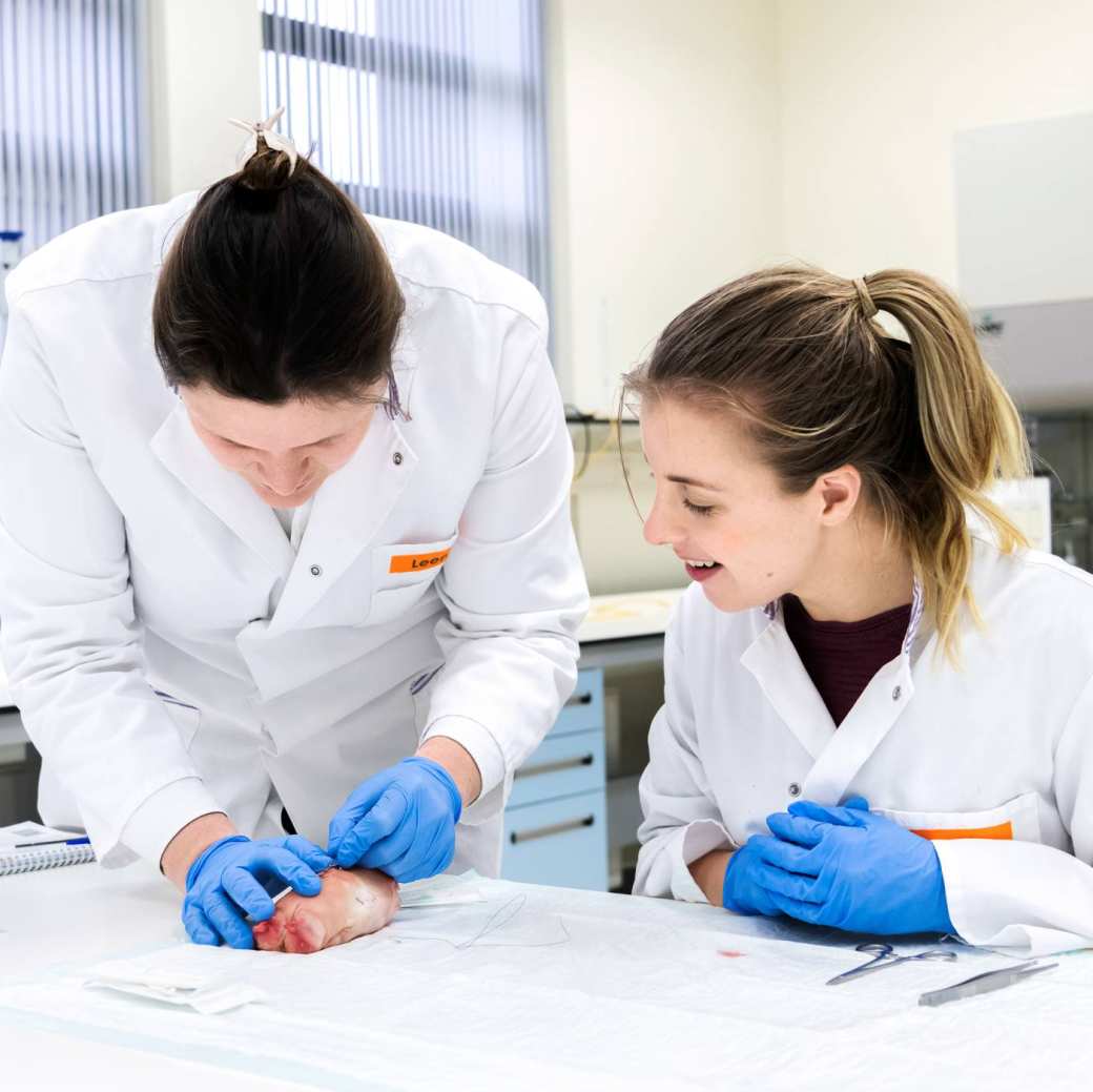 Een docent demonstreert een hechttechniek aan een Physician Assistant in opleiding