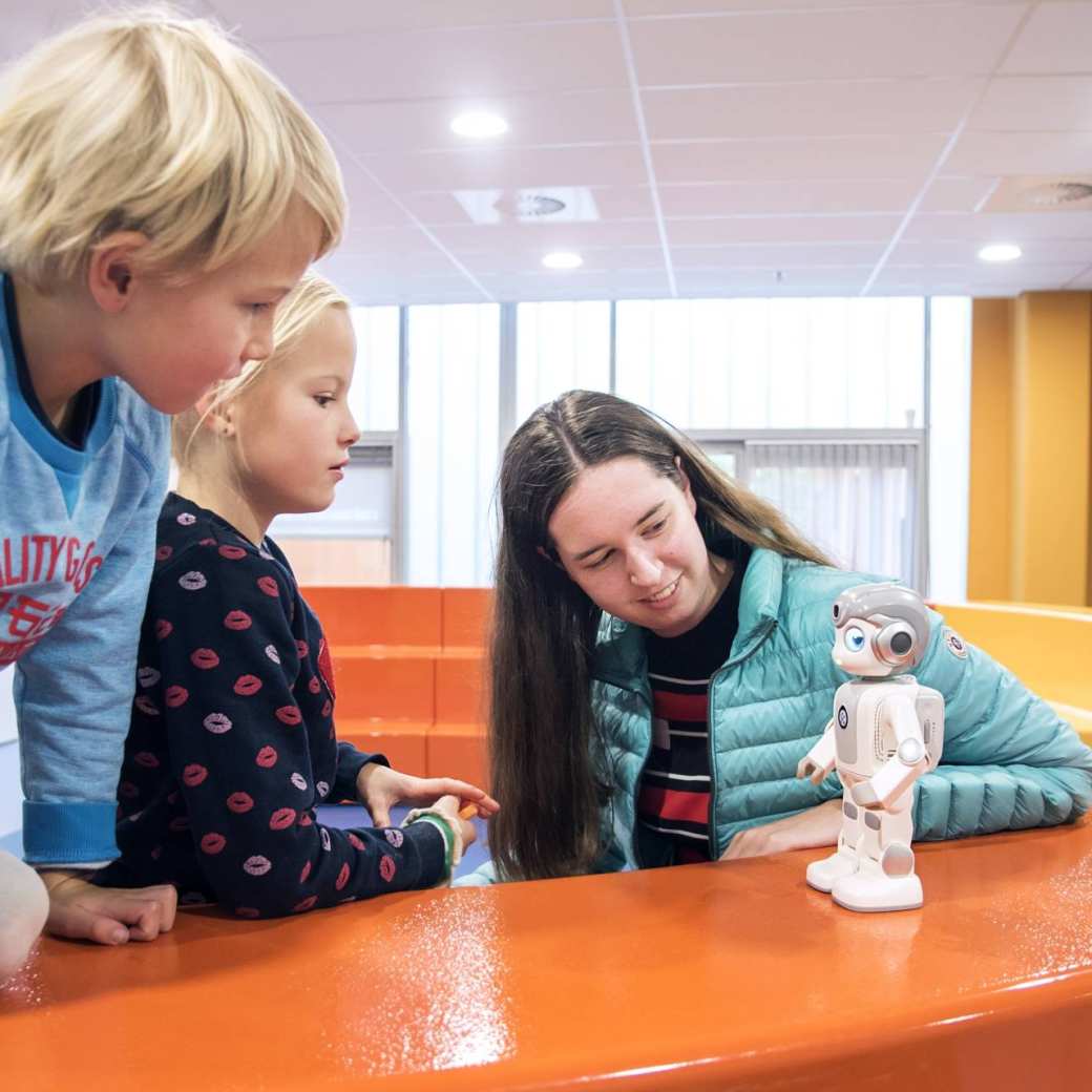 zit op balie, meisje en student kijken naar kleine zorgrobot