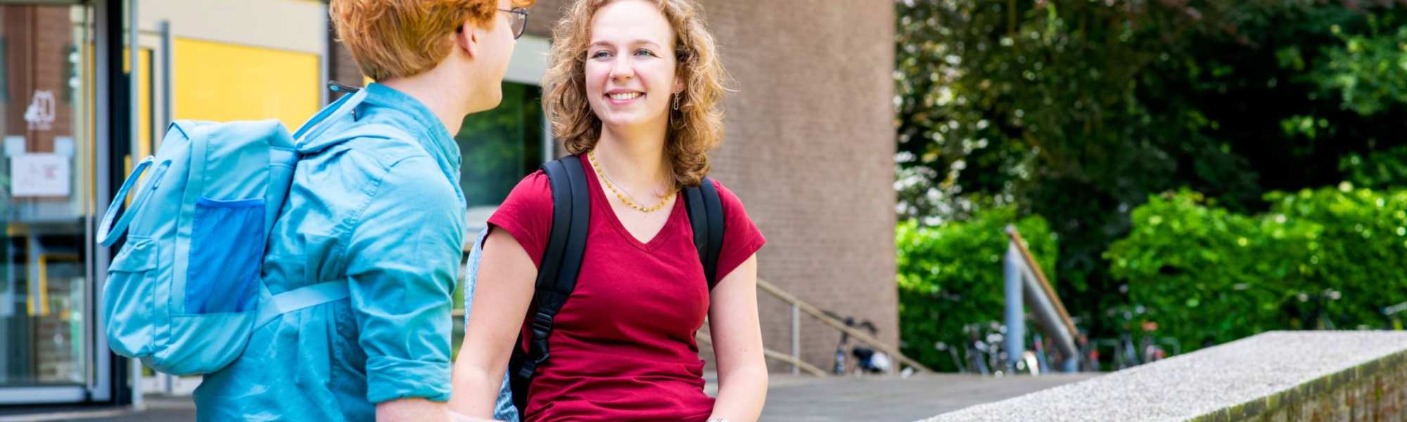 Een student met blonde krullen lacht. 