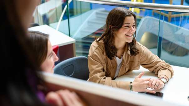 Een studente zit lachen aan tafel op de campus in Nijmegen