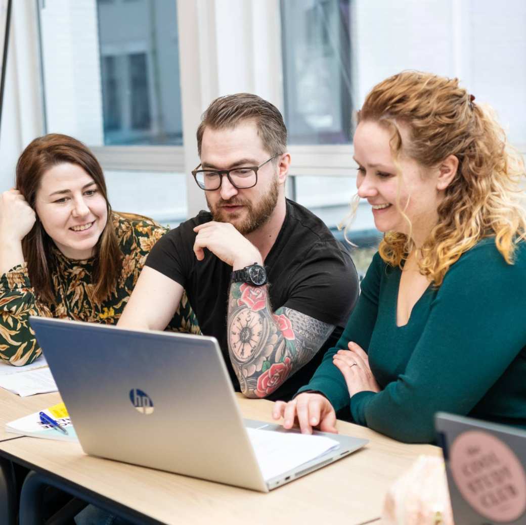 Drie studenten van de Master Advanced Nursing Practice werken samen op een laptop tijdens de les onderzoek op de HAN