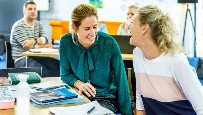 Twee studenten schaterlachen met elkaar.