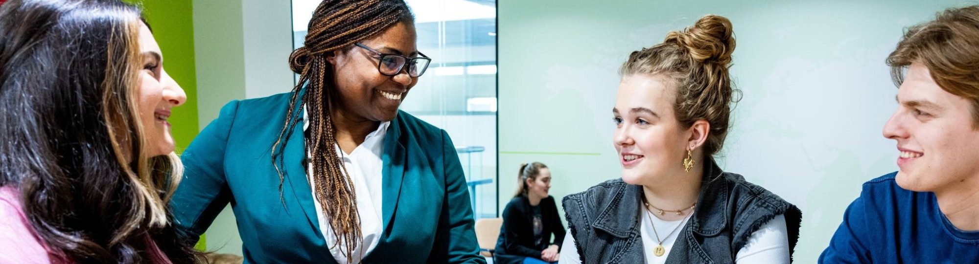 Een docent legt drie studenten iets uit.