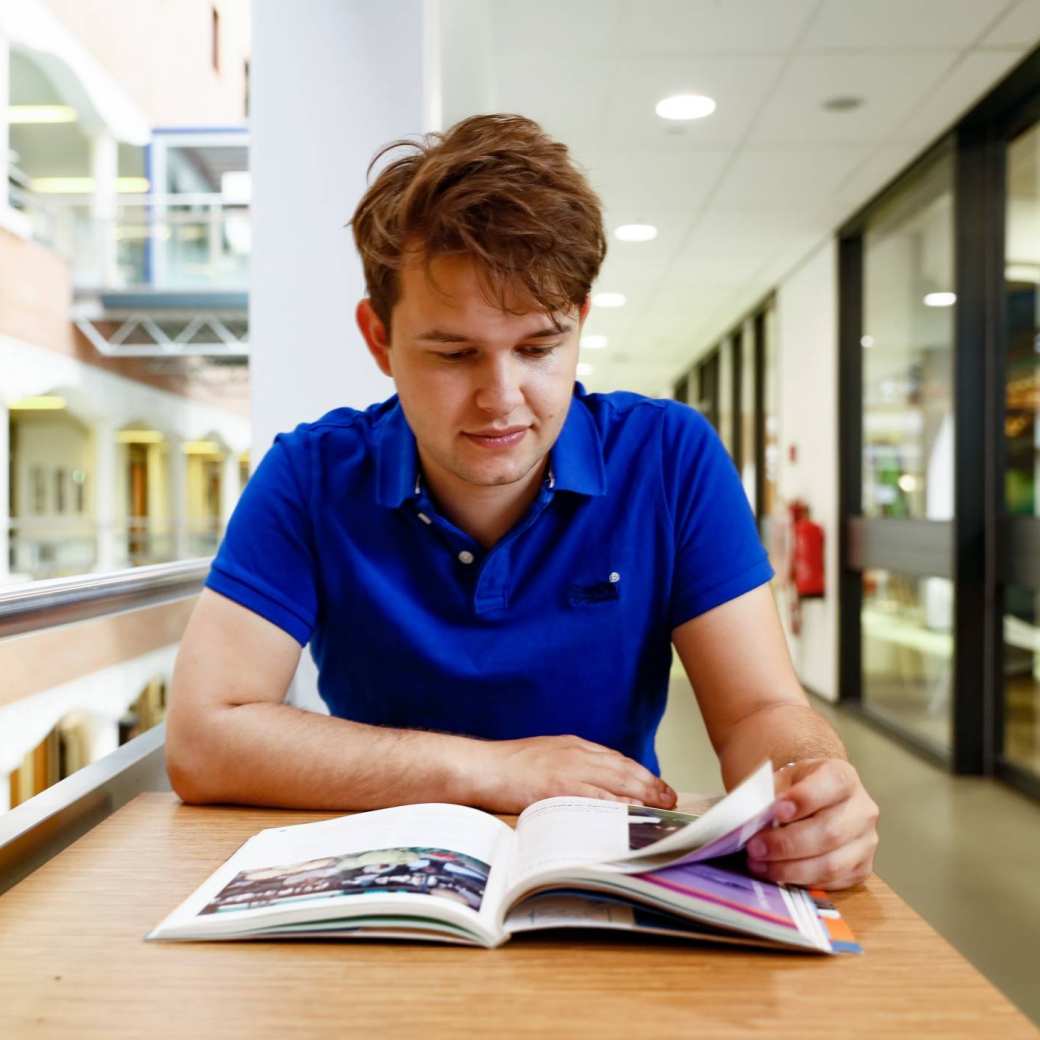 student man leest boeken hal