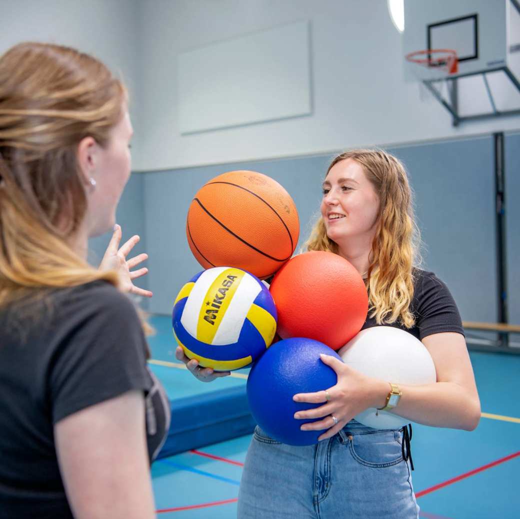 2 meisjes met ballen in gymlokaal