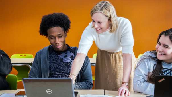 Foto Master Academie Educatie. Docent wijst op laptop scherm, terwijl 2 studenten kijken. 