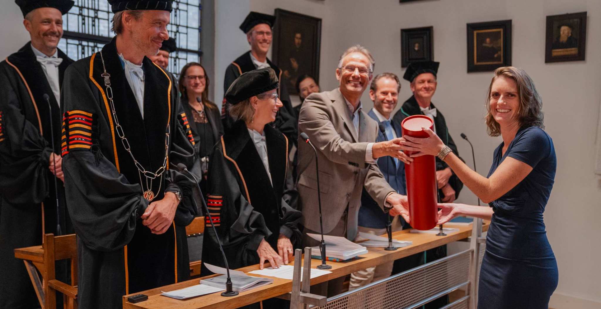 Onderzoeker Ilona Schouwenaars voor een groep mensen en krijgt een rol uit handen van lector Jan Pieter Teunisse. Beide lachen in de camera