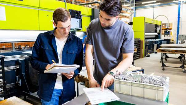 Twee Technische Bedrijfskunde studenten overleggen op de werkvloer.