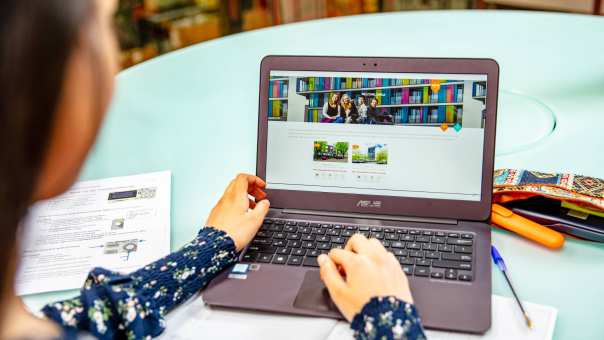 Student achter laptop met book your room app