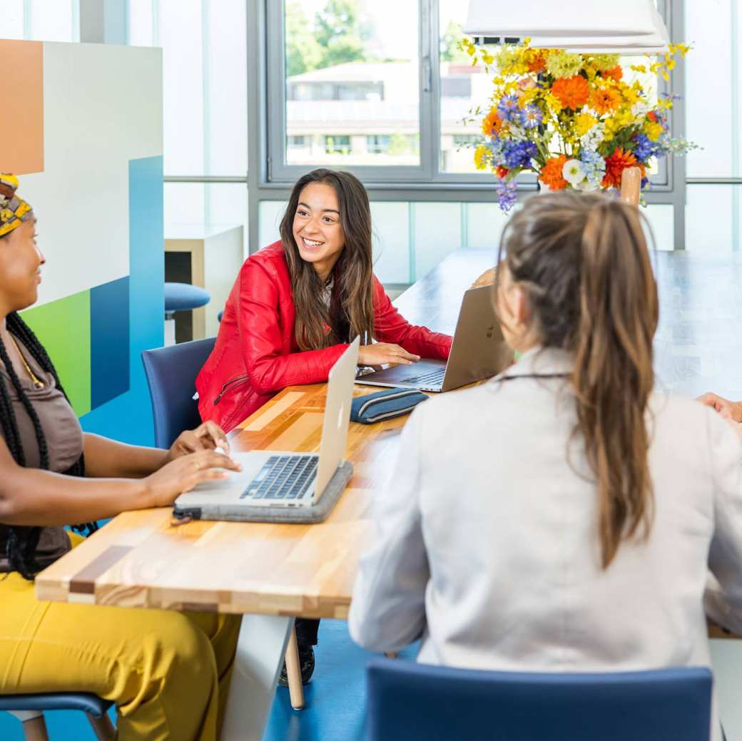 Lo-res. Groep van 4 studenten in overleg aan tafel in algemene ruimte HAN. 