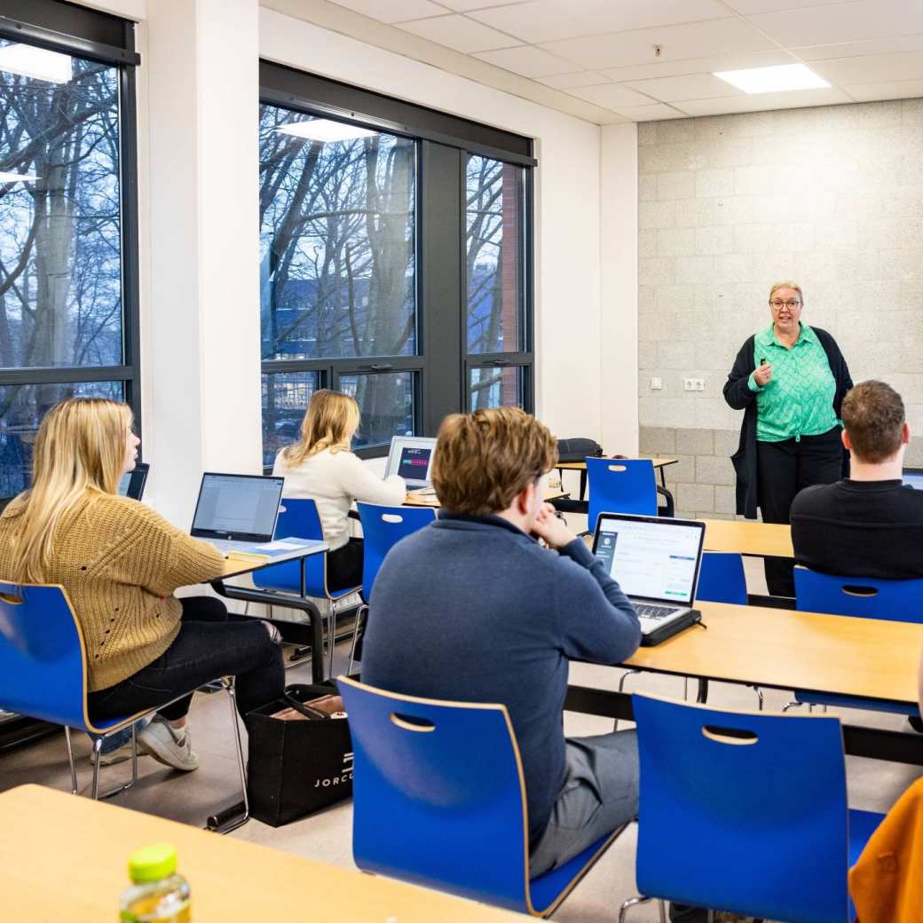 Klaslokaal met docent en deeltijd studenten die kijken op laptop