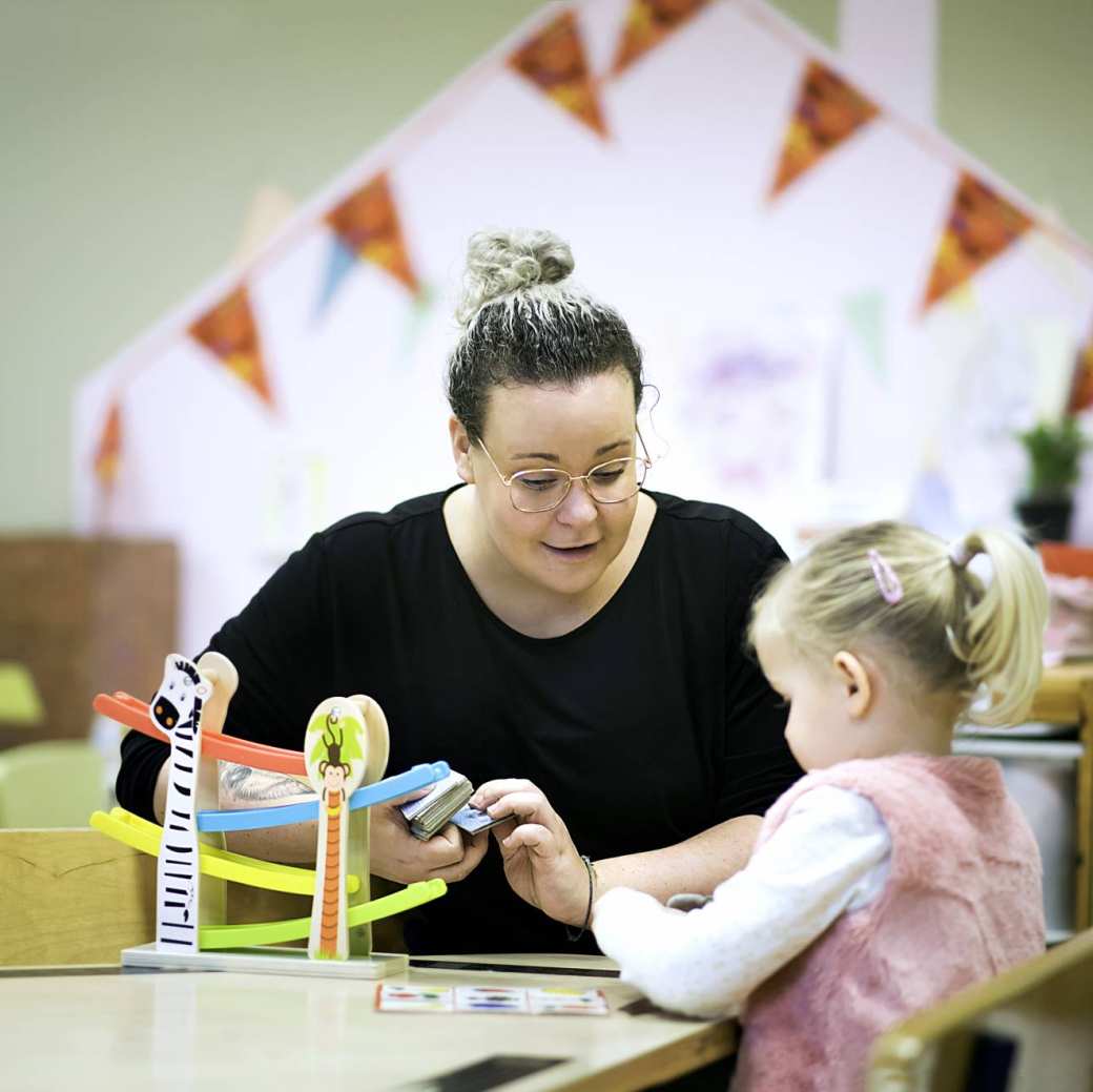 Een docente en een kind spelen een spel.