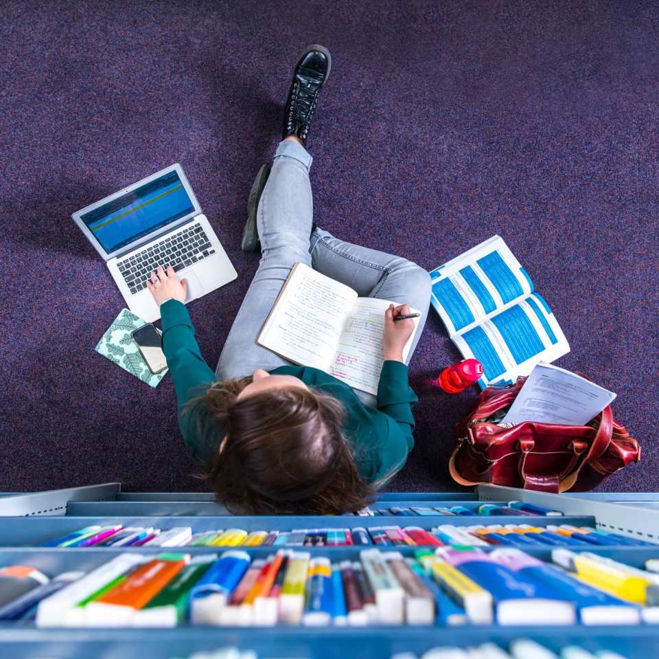 Studente studeren in studiecentrum en werken op laptop, van bovenaf