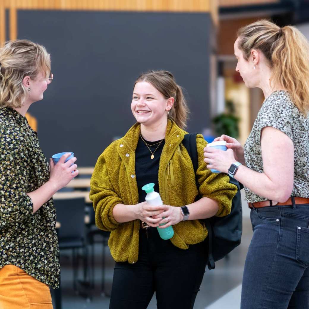 Drie studenten staan te kletsen in de hal