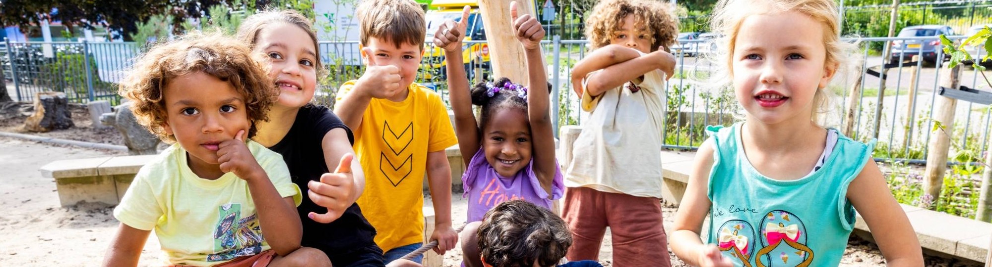 Zeven kinderen poseren buiten op het klimnet