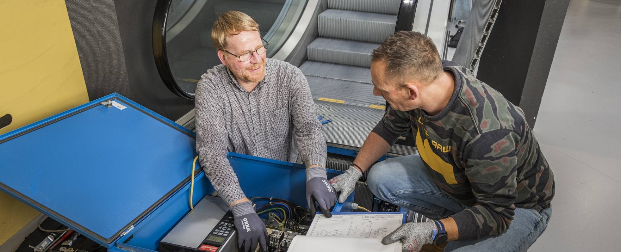 Twee cursisten voor het praktijkexamen BOEI in overleg voor een roltrap.