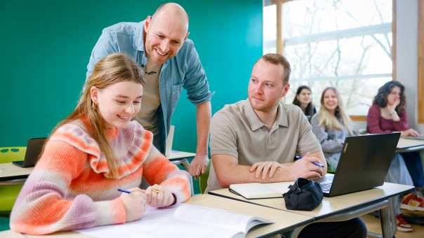 Docent kijk mee over de schouder van studenten