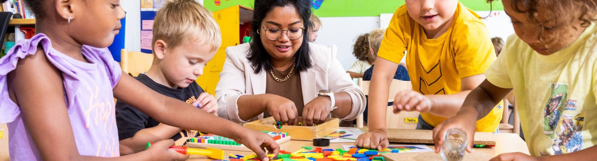 De leerlingen leggen een puzzel en de lerares helpt hen hierbij