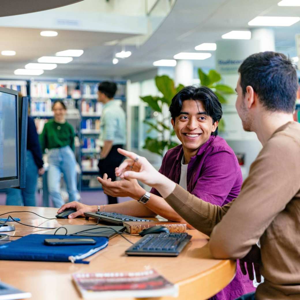 International students Diego and Andrei looking for information in the library at the Arnhem campus of HAN University of Applied Sciences.