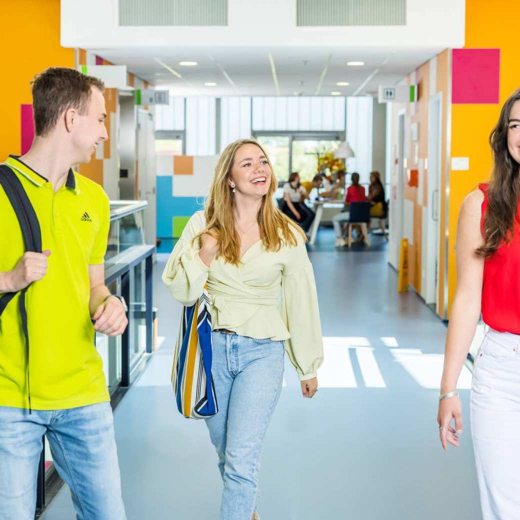 Drie studenten (2 jongen en 2 meiden) wandelend in gang K33. 