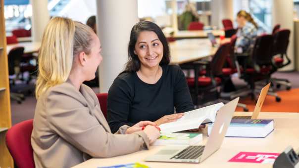 Twee studenten in de bibliotheek aan het overleggen voor de studie PMT deeltijd