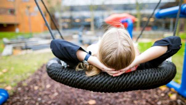 Een foto van student Meike Geurts die zit te relaxen op een schommel in een speeltuin.