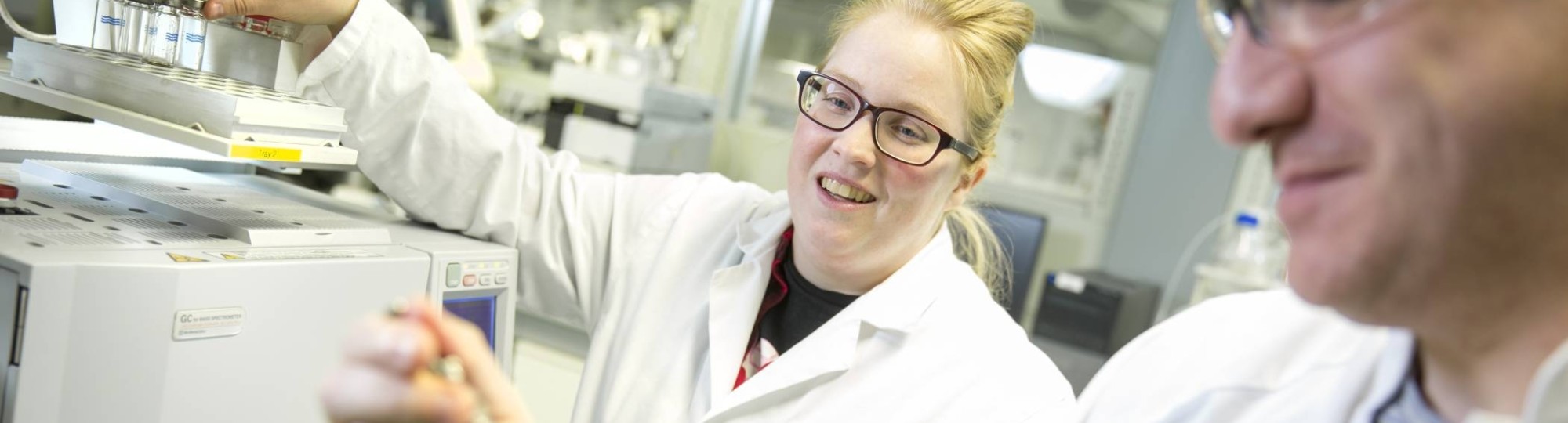 blonde vrouw en man in laboratorium pipetteren