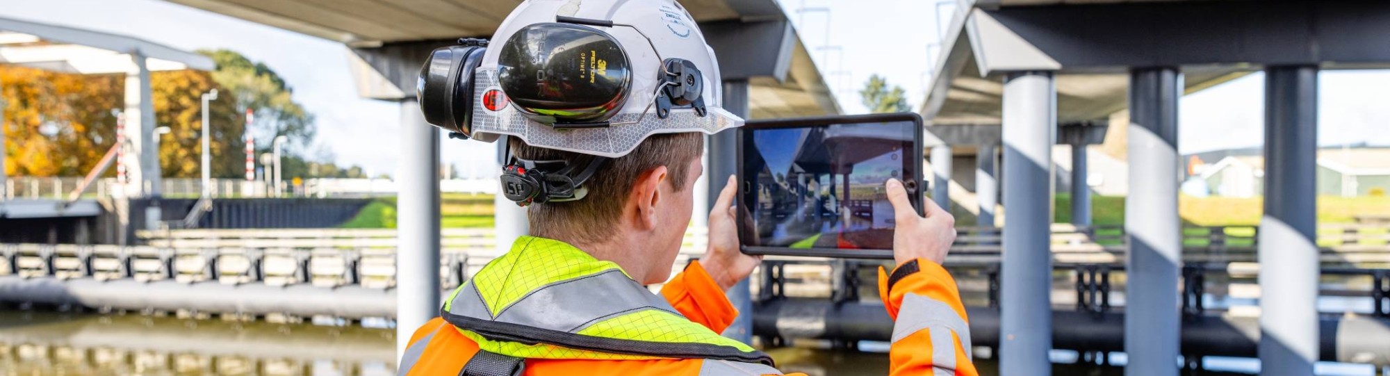 Man met tablet bij een brug