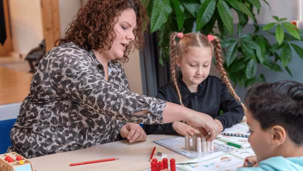 Associate Degree Pedagogisch Educatief Professional (AD PEP) legt wat uit aan tafel met twee leerlingen