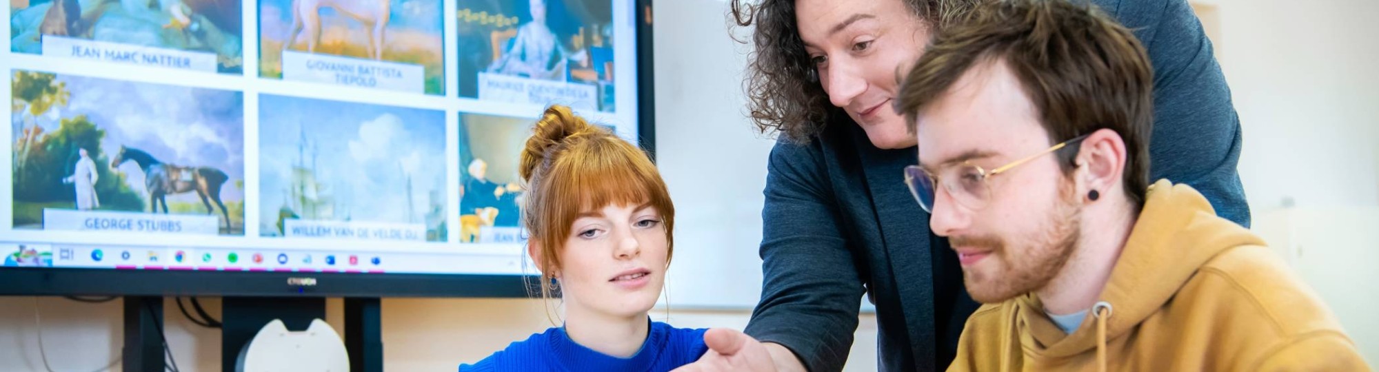 Twee studenten lachen met elkaar tijdens het werken achter de laptop.