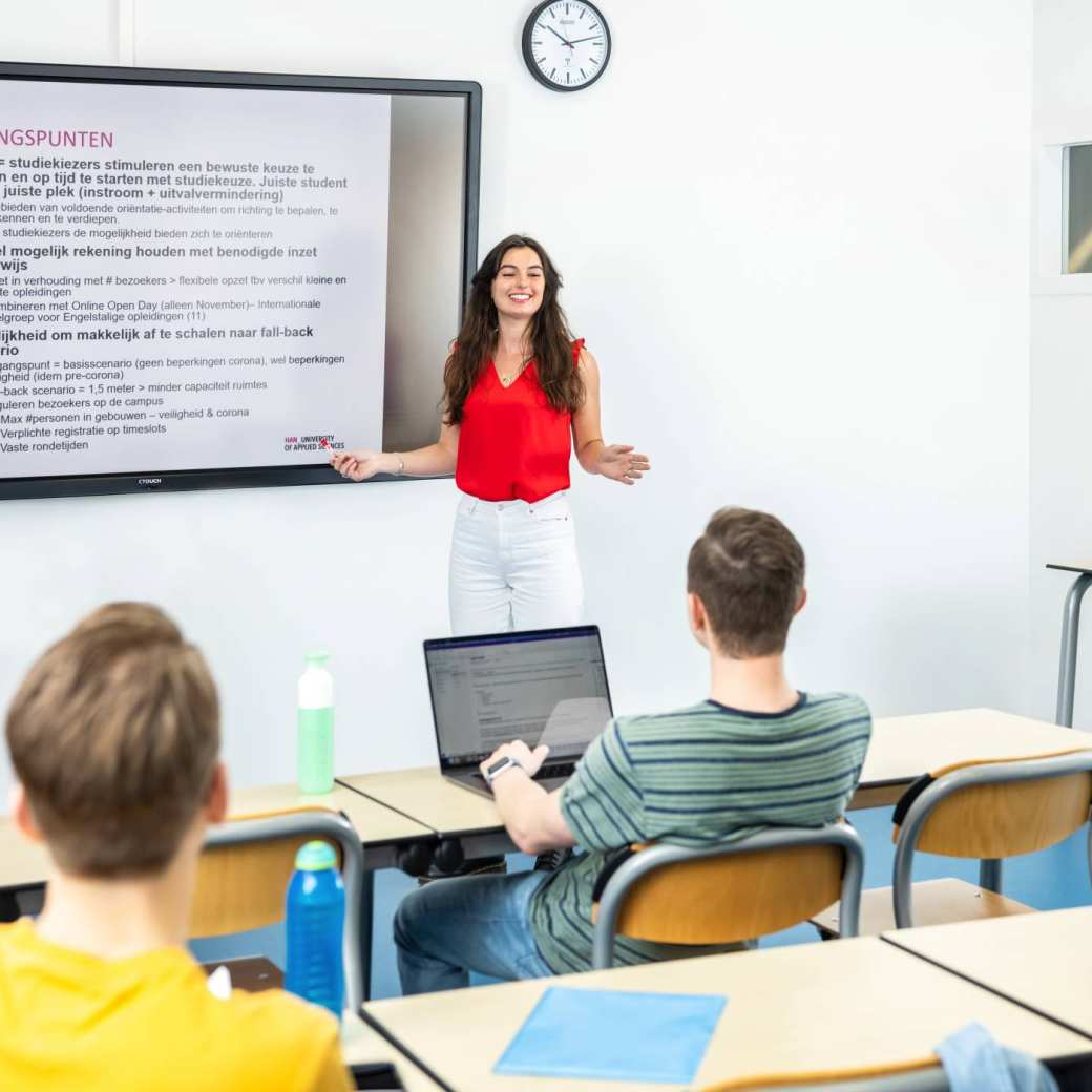 Studente geeft presentatie aan medestudenten in leslokaal. 